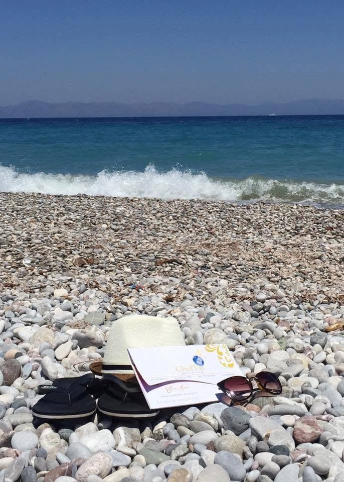 GhidTur travel materials on a pebble beach.
