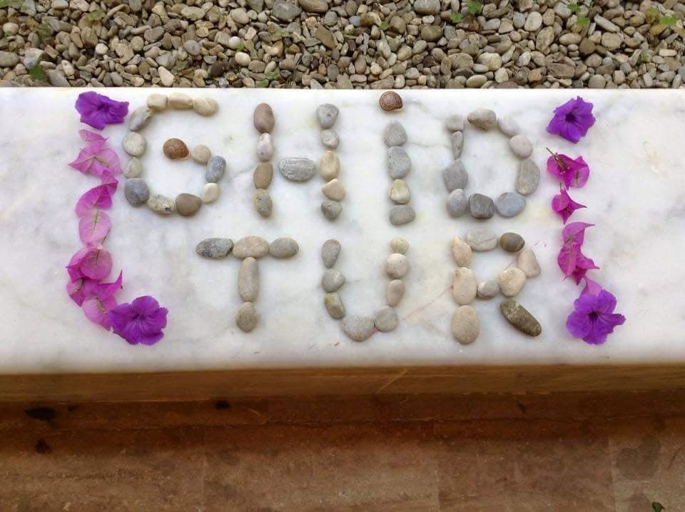 GhidTur spelled in stones and framed with purple flowers.